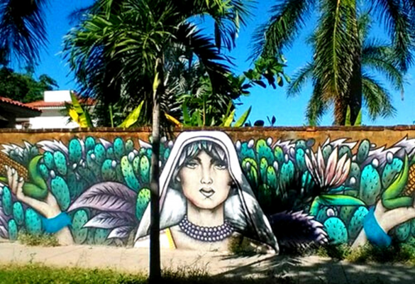 A mural of a veiled woman holding corn painted on a brick wall